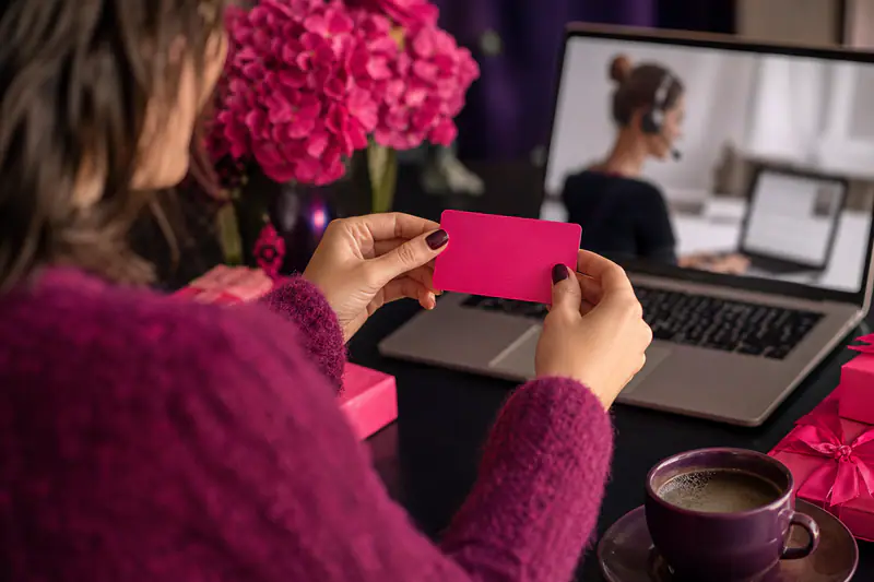 Mains tenant une carte cadeau, ordinateur portable ouvert en arrière-plan