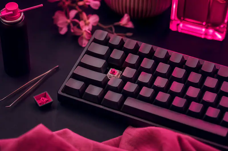 Clavier mécanique avec une touche retirée montrant le mécanisme, bombe d’air comprimé posée à côté