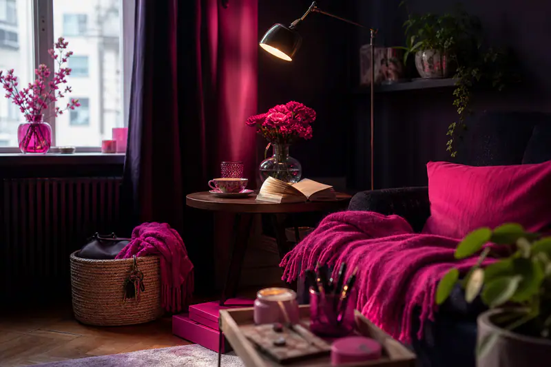 Salon lumineux et rangé avec plantes, lampe chaude, livre et tasse de thé