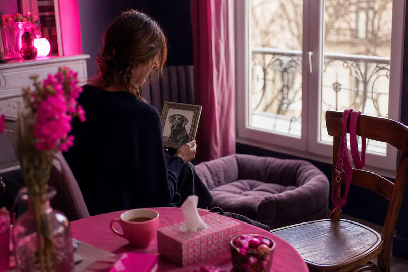 Femme recueillie près du panier vide de son chien en hiver