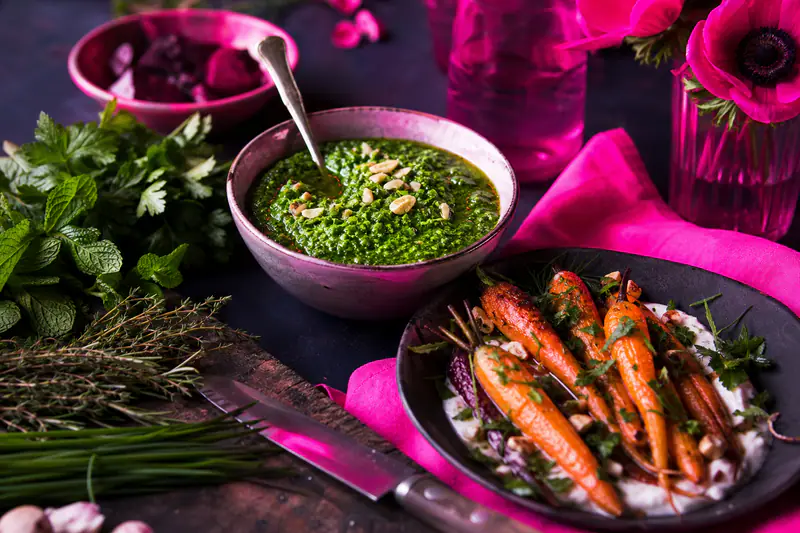 Herbes fraîches, pesto vert et carottes rôties sur un plan de travail