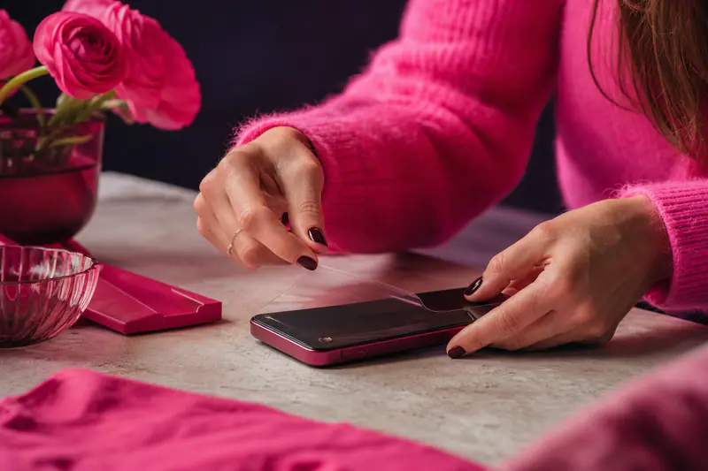 Mains retirant une protection d’écran de smartphone avec une bulle d’air visible au bord