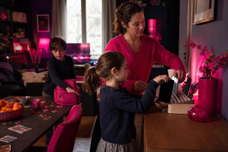 Famille déposant téléphones et tablette dans une station de recharge commune