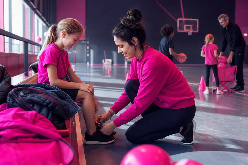 Une mère prépare sa fille avant une séance multisport en gymnase.
