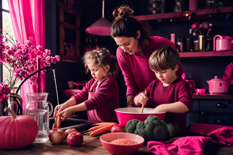 Deux enfants préparent des légumes d’automne avec leur mère dans une cuisine.