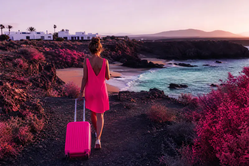Voyageuse arrivant sur une crique volcanique des Canaries avec sa valise