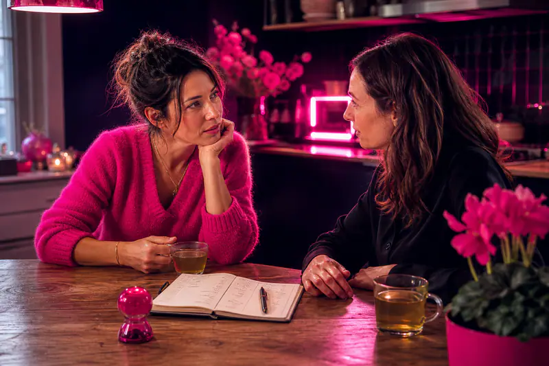 Deux amies s’écoutent autour d’un carnet et de tasses de thé.