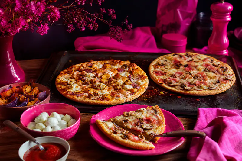 Deux pizzas sans gluten aux garnitures d’automne sur une plaque chaude.