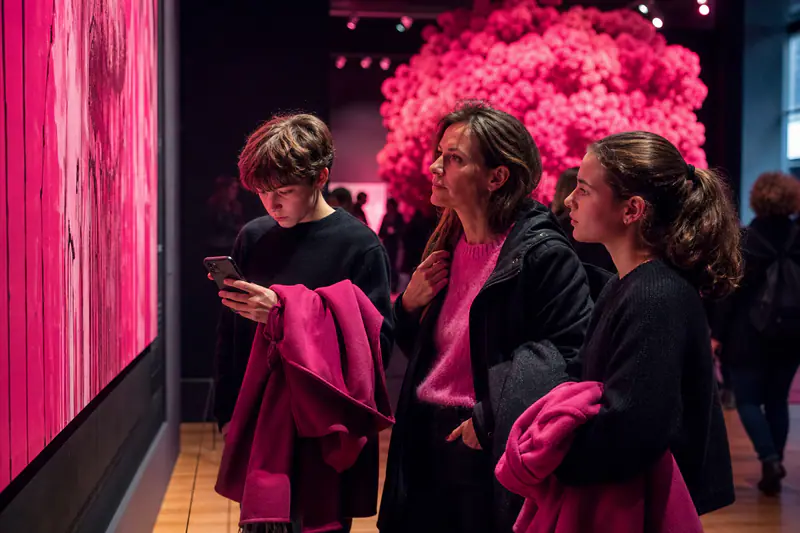 Une mère et deux adolescents observent une œuvre dans un musée contemporain.