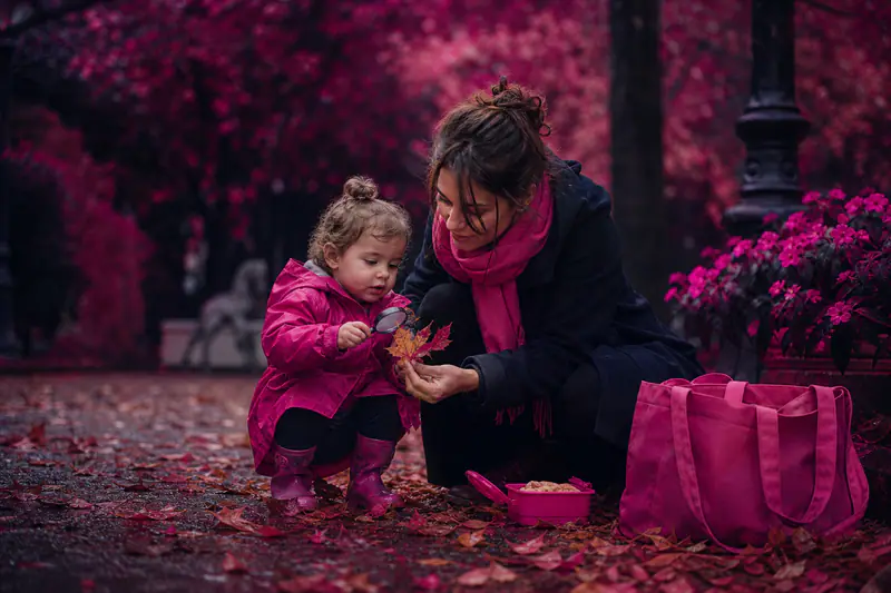Mère et tout-petit observent des feuilles d’automne dans un parc.
