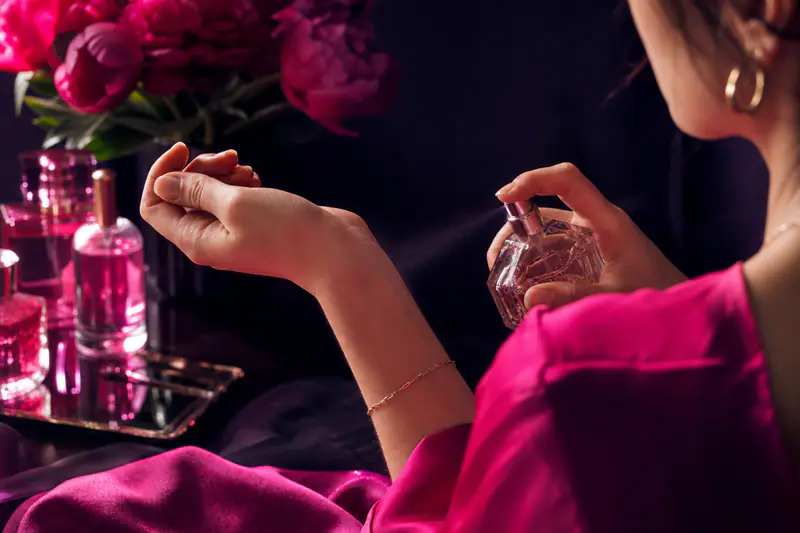 Flacon de parfum vaporisé sur un poignet, dans une lumière douce