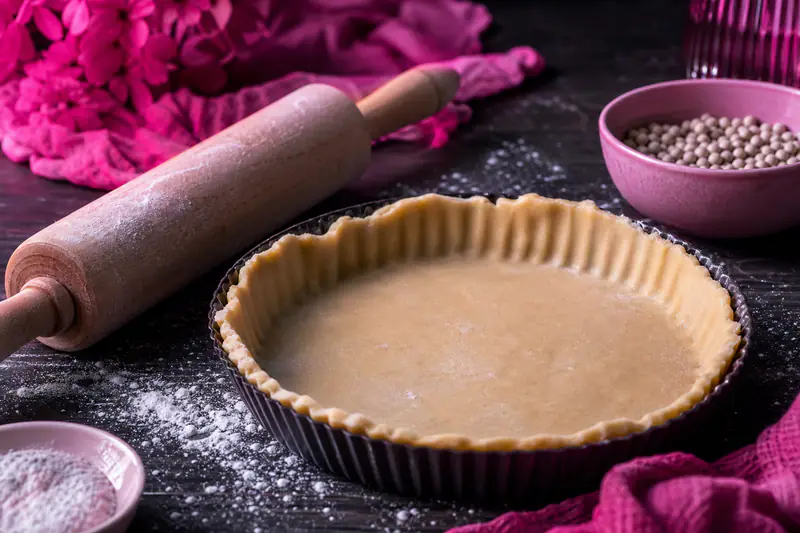 Fond de tarte dans un moule cannelé dont les bords se sont légèrement rétractés