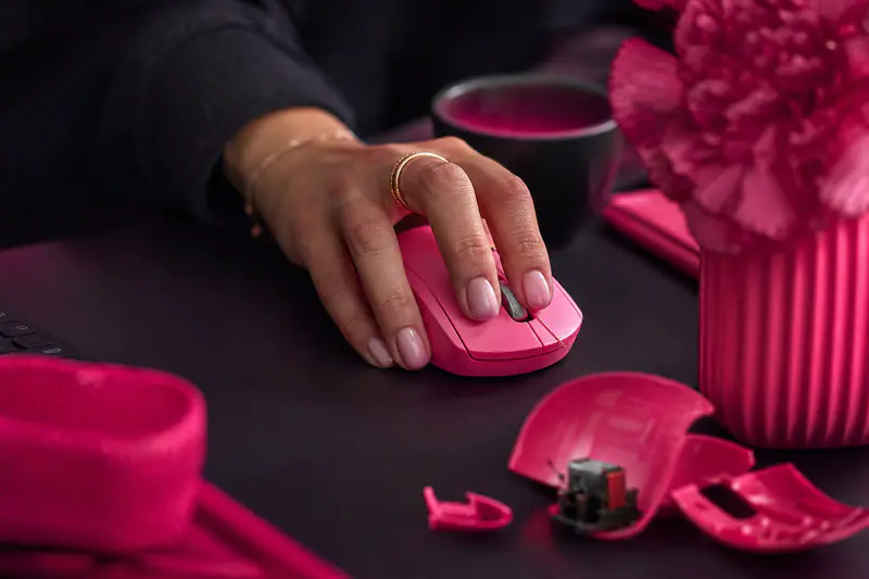 Main cliquant sur une souris d’ordinateur, avec un switch démonté visible en arrière-plan