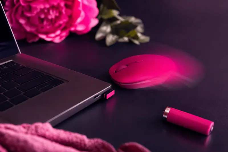 Souris sans fil et son récepteur USB posés sur un bureau, pile de rechange à côté