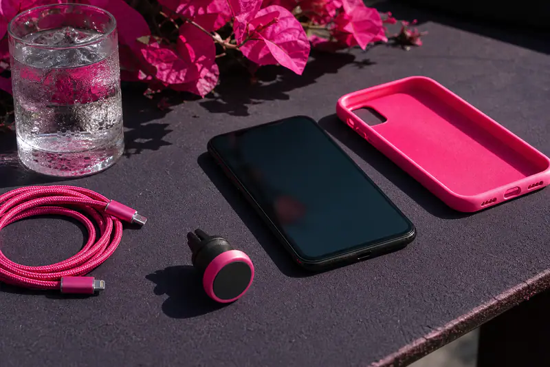 Smartphone à l’écran assombri posé au soleil, sa coque et son câble retirés à côté